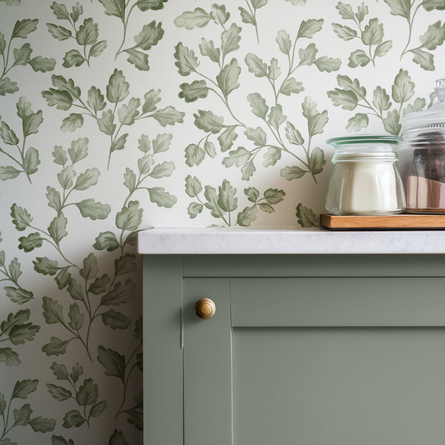 Green cabinet with white countertop against a leaf-patterned wall