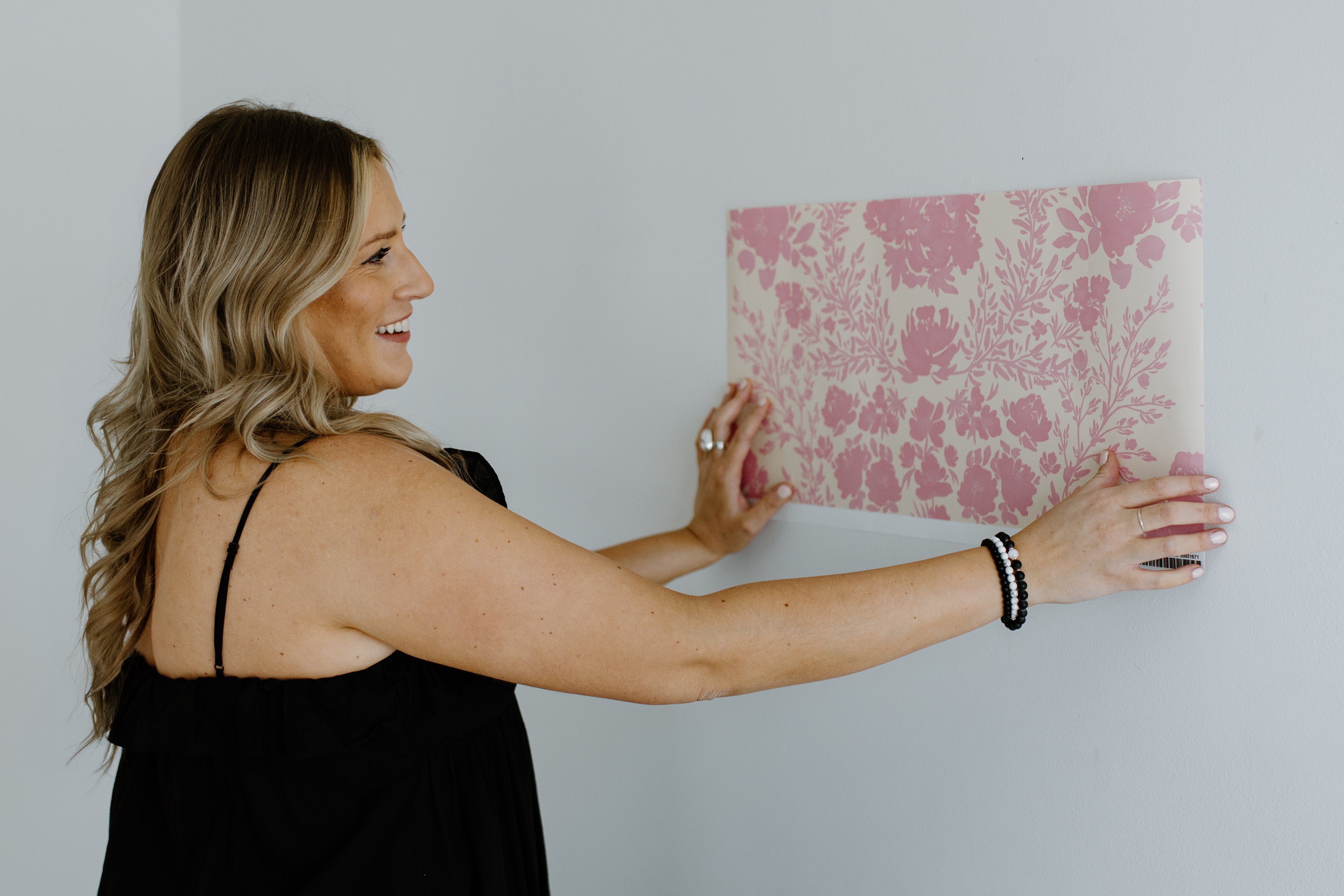 Sabina Maria, holding a pink floral patterned paper against a white wall