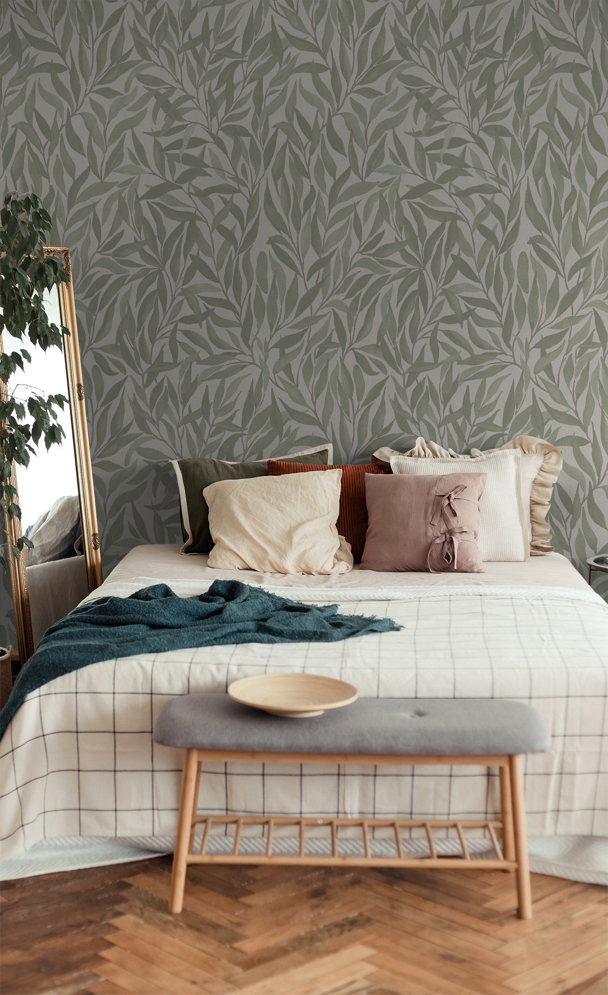 Green leaf pattern wallpaper in cozy bedroom with pillows and bench