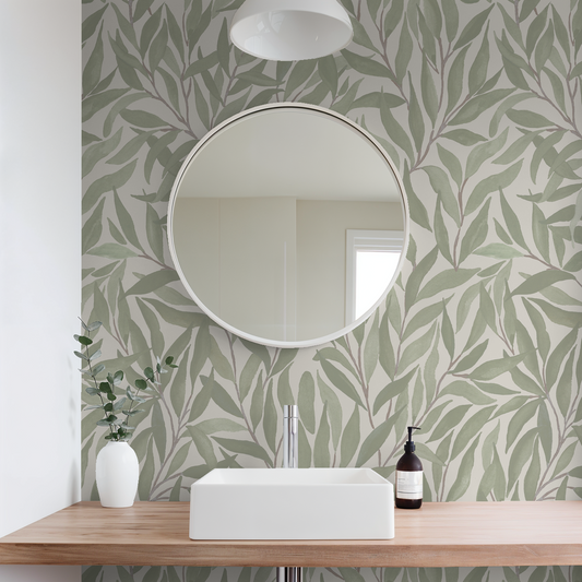 Green leaf patterned wallpaper in modern bathroom with round mirror and wooden vanity.