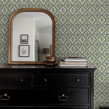 Ivory wallpaper with green lattice and blue blossoms in a vintage room setting.